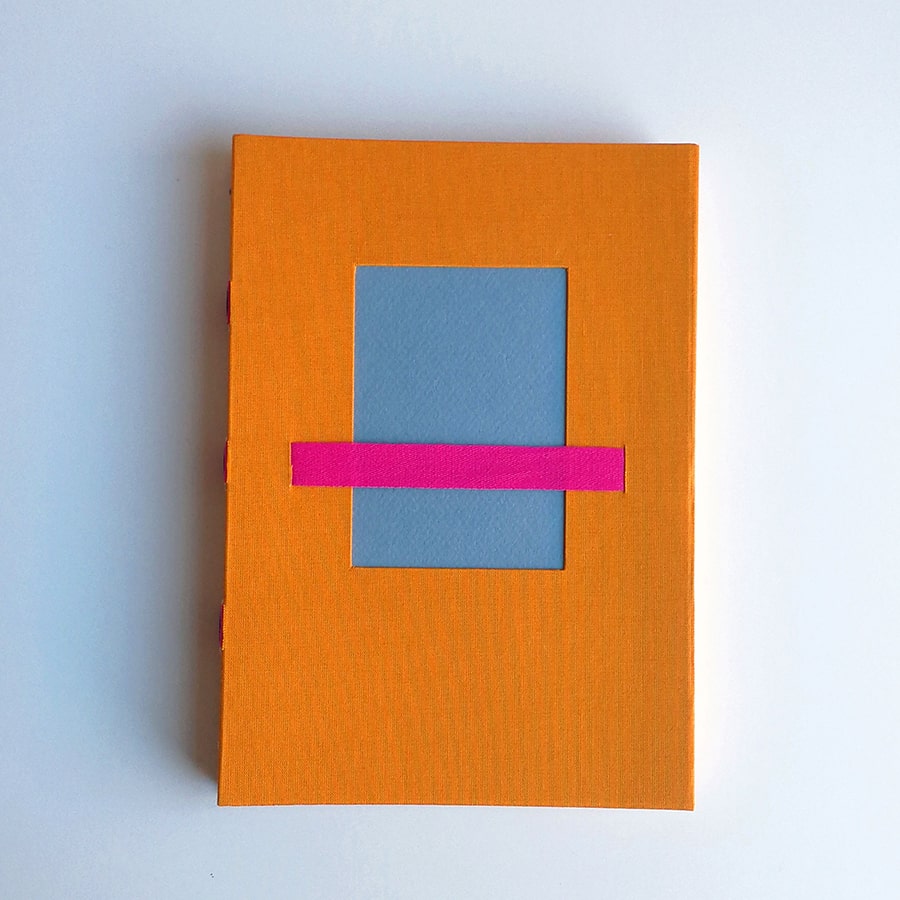 cuaderno A5 naranja ventana azul grisaceo y cinta magenta